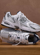 New Balance Women's 530 Sneaker in White/Natural Indigo Two Sneakers Shown Stacked on Top of Each Other