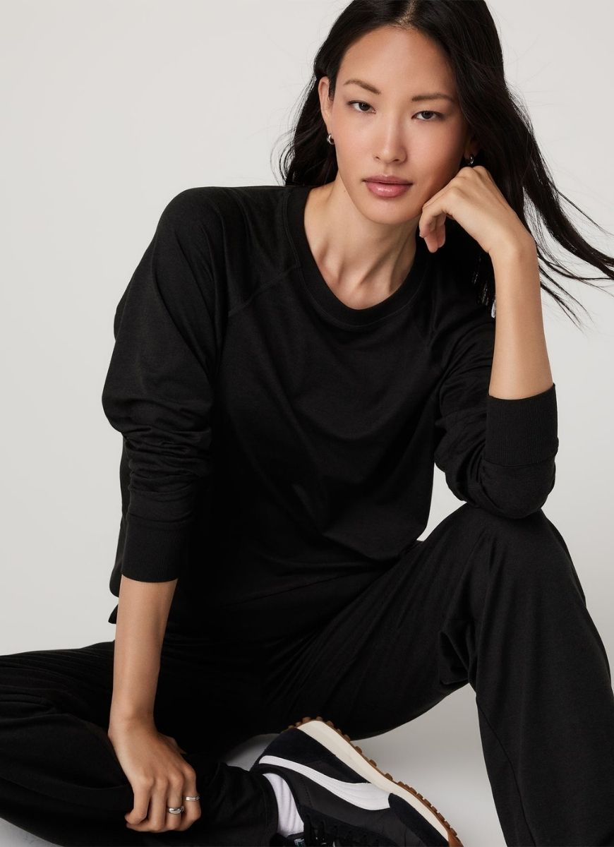 Vuori Women's Long Sleeve Halo Crew in Heather Black Front View With Model Sitting Down in a Pose