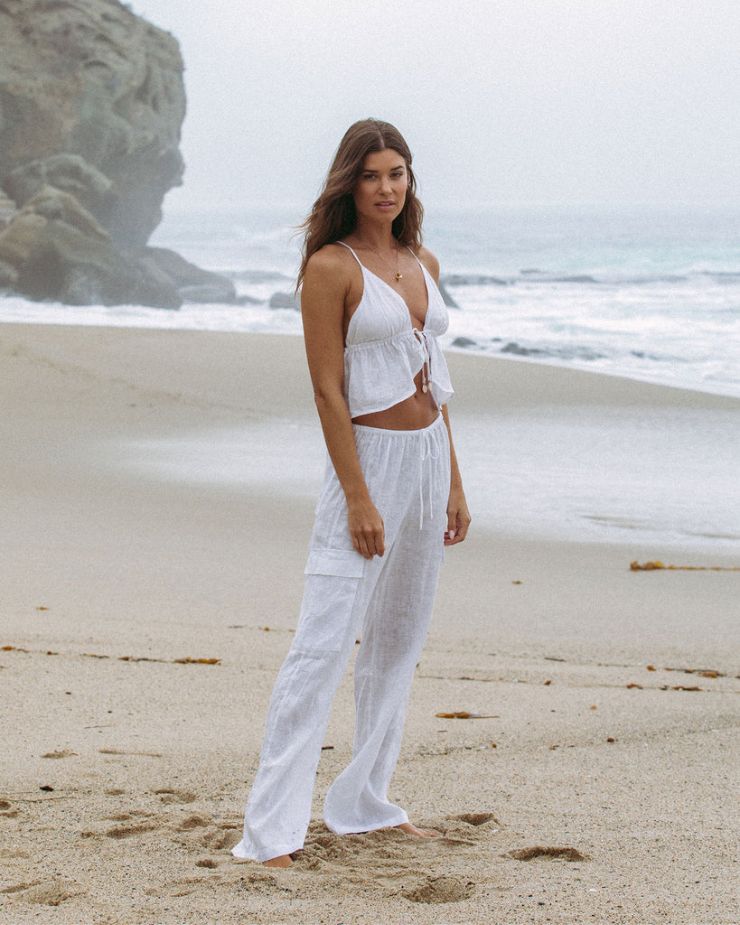 Model Standing on the Beach Wearing the LSPACE Sundown Top and Sundown Cargo Pant in White