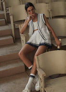 Varley Mariam 2-in-1 Court Skirt 14.5” in White/Blue Nights Model Posing Sitting in a Chair