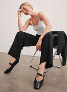 Beyond Yoga Easy Wide Leg Pant in True Black Shown With Model Sitting on a Chair