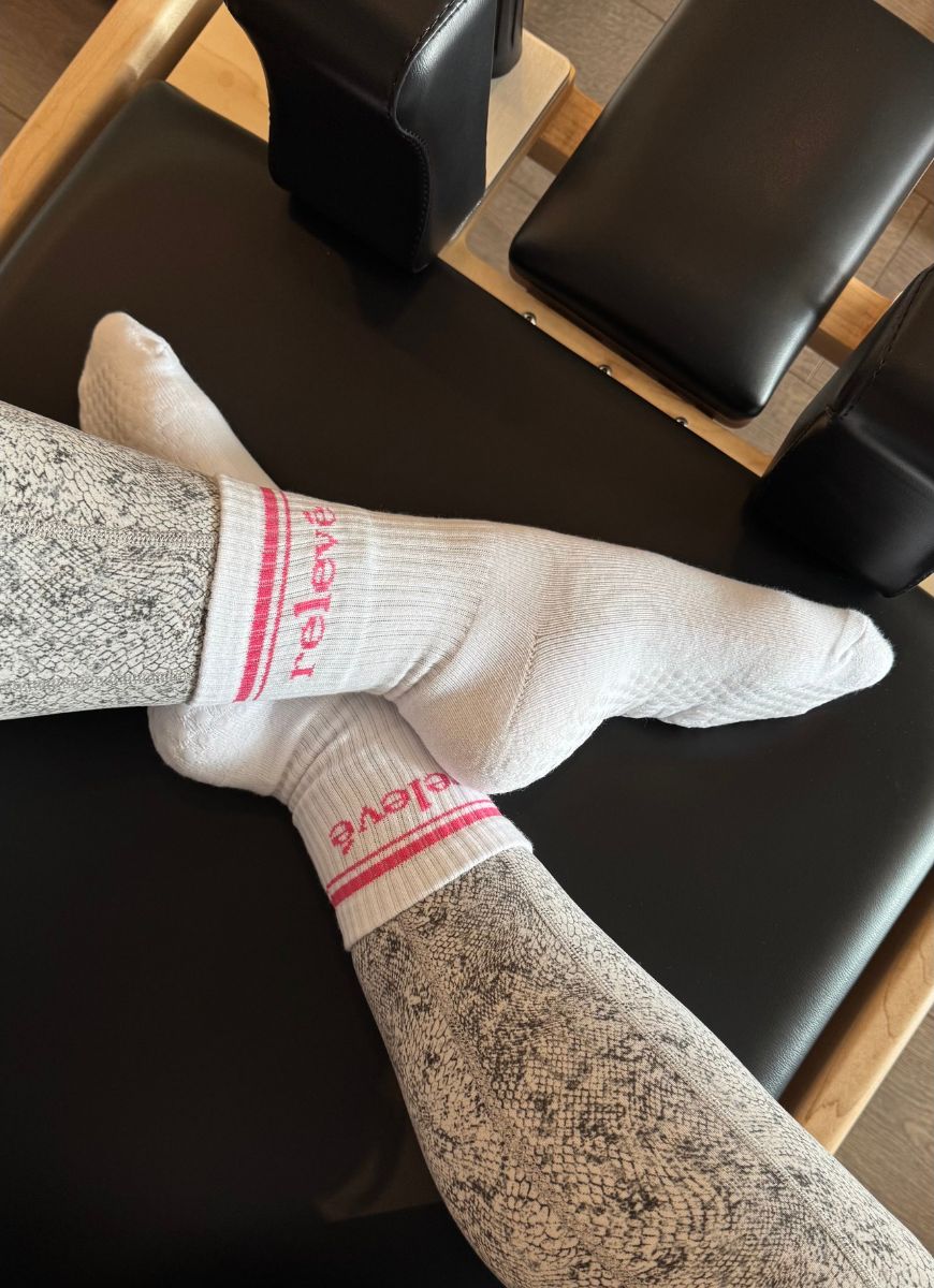 relevé Grip Socks in White with Pink Logo Shown on a Reformer Machine