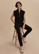 Varley Loretta Sleeveless Half Zip in Black Model Sitting on a Stool