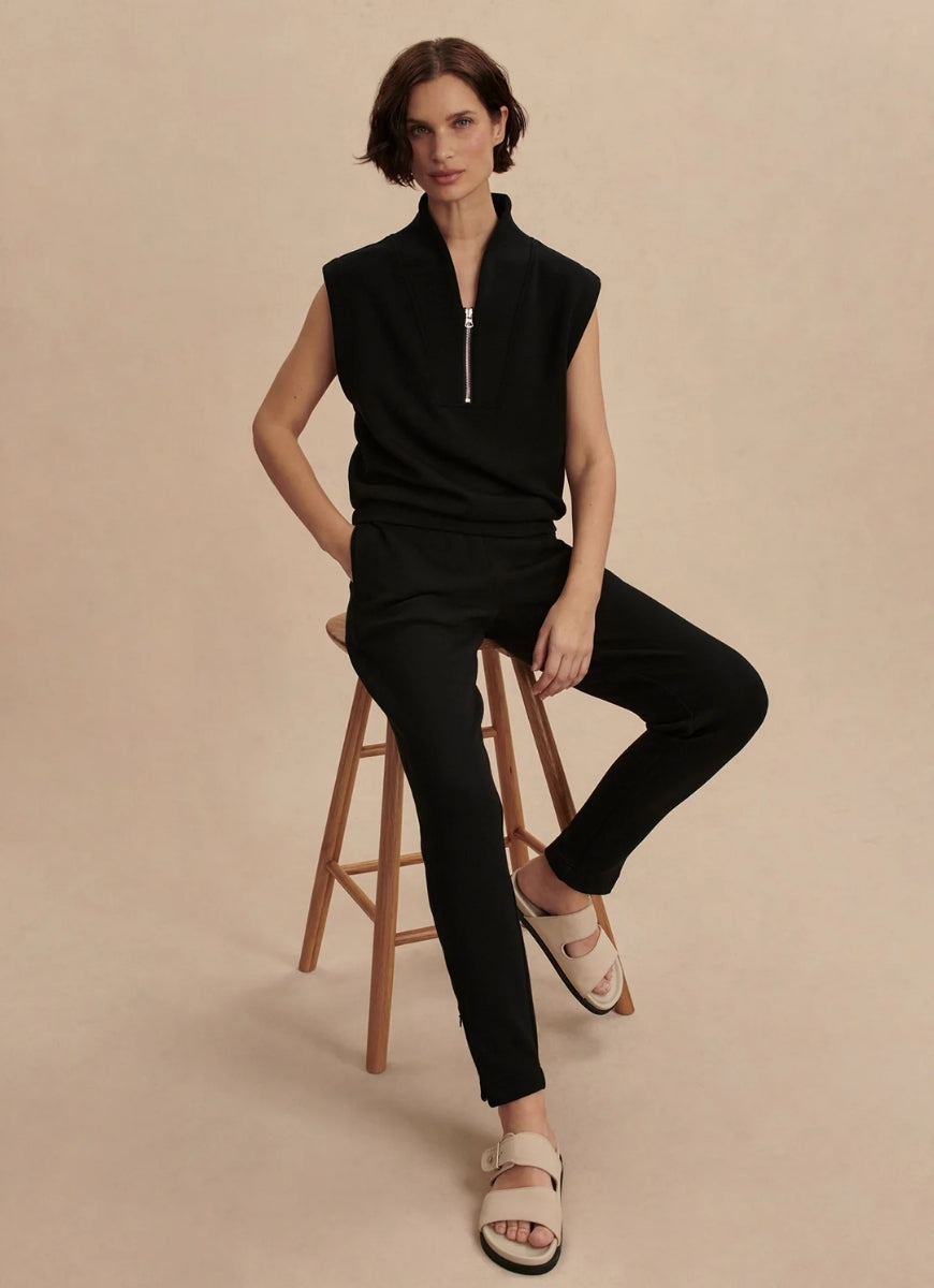 Varley Loretta Sleeveless Half Zip in Black Model Sitting on a Stool