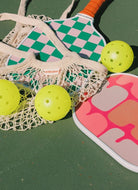 On Holiday Ibiza Pickleball Paddle Shown on a Green Court With Yellow Balls