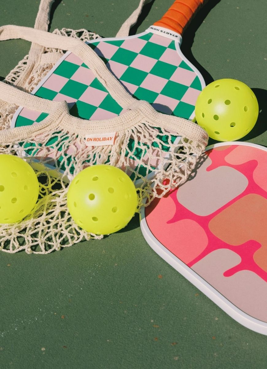 On Holiday Ibiza Pickleball Paddle Shown on a Green Court With Yellow Balls
