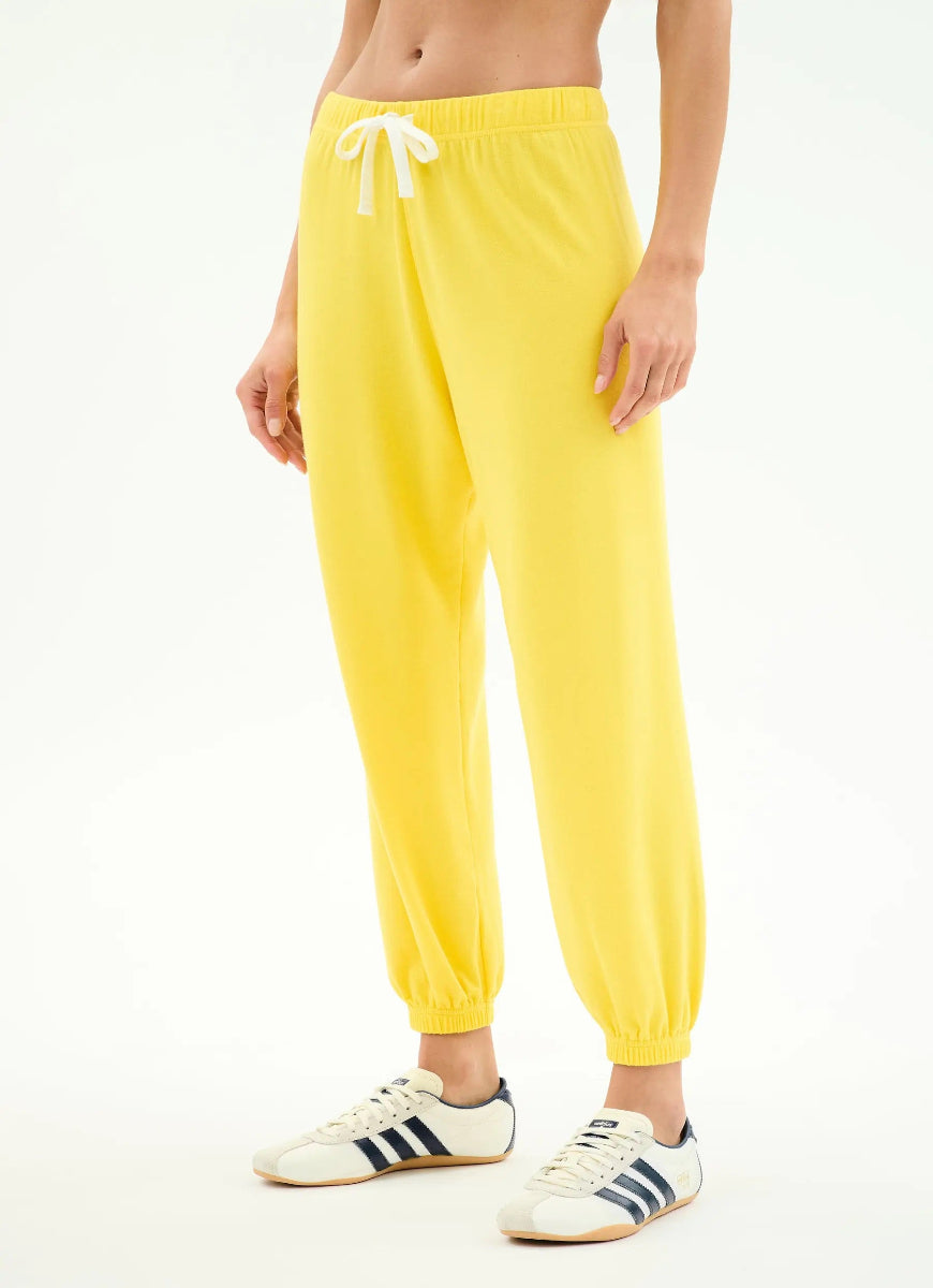 Person wearing bright yellow sweatpants with a white background
