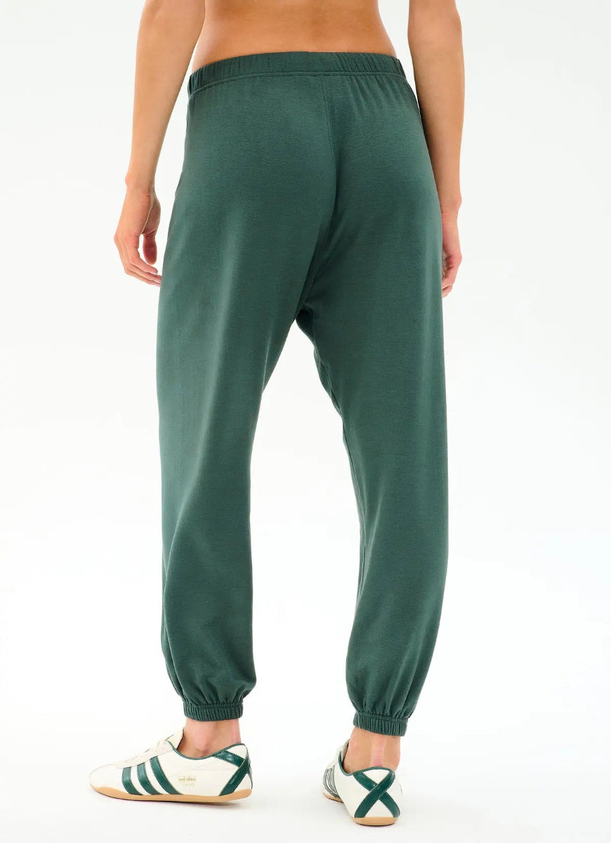 Green sweatpants worn by a person on a white background