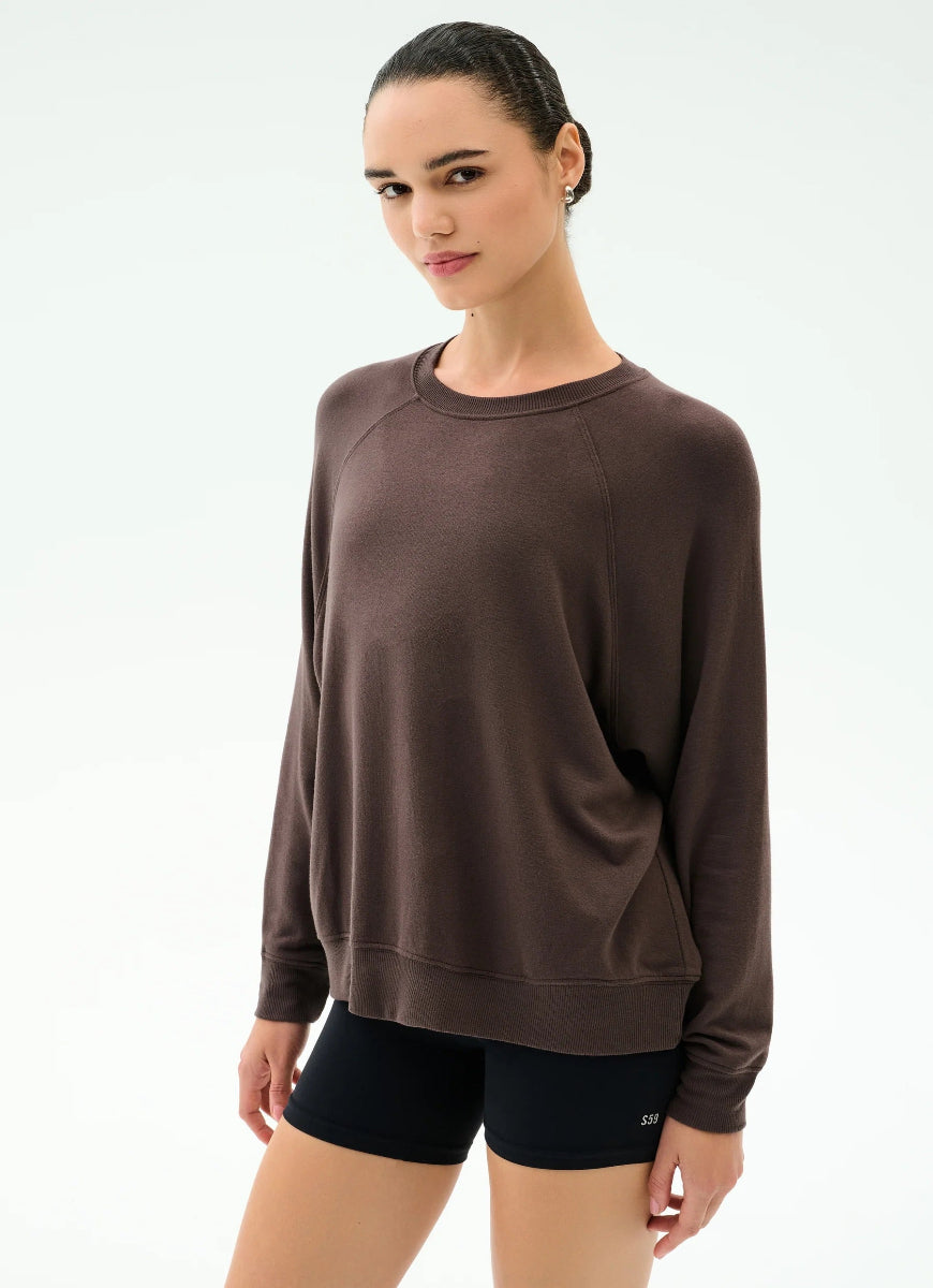 Woman wearing a brown sweatshirt and black shorts on a white background