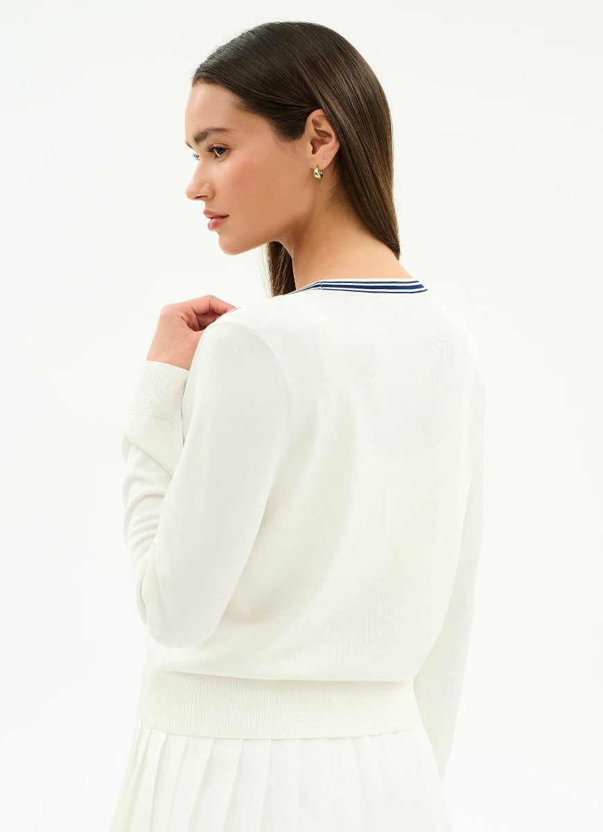Woman wearing a white long-sleeve top with a blue trim on a white background