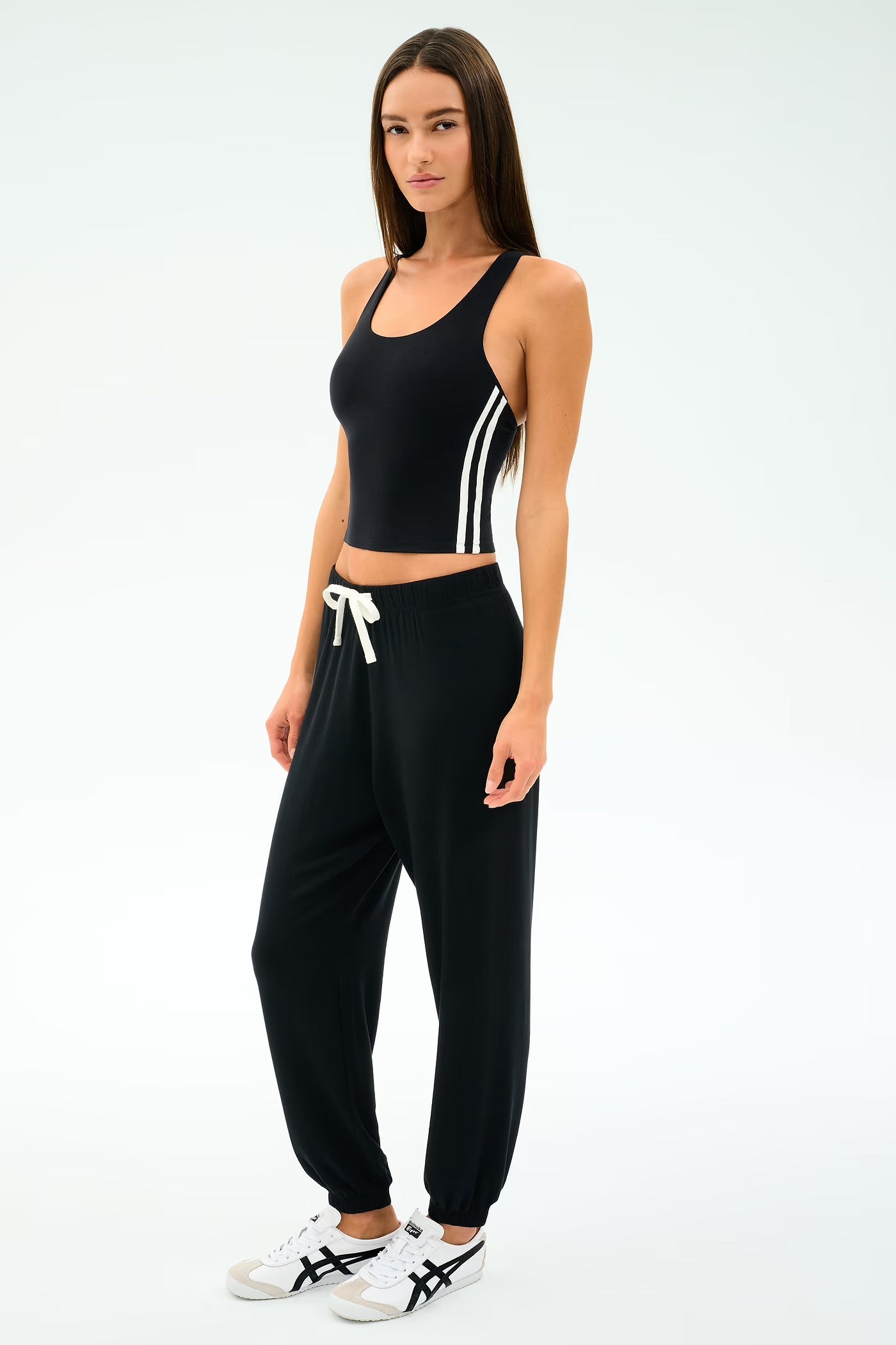 Woman wearing a black athletic outfit with white accents on a white background