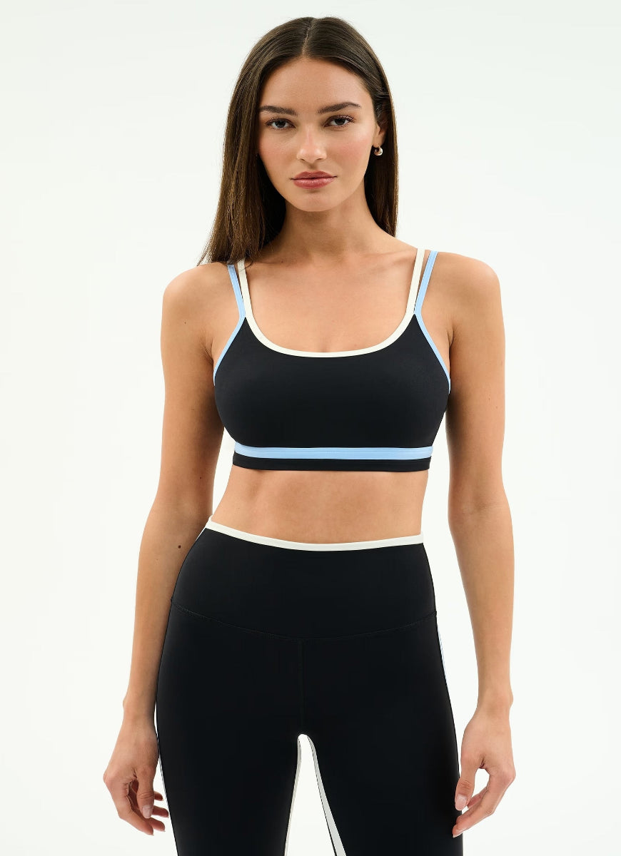 Woman wearing a black sports bra with white and light blue accents on a white background