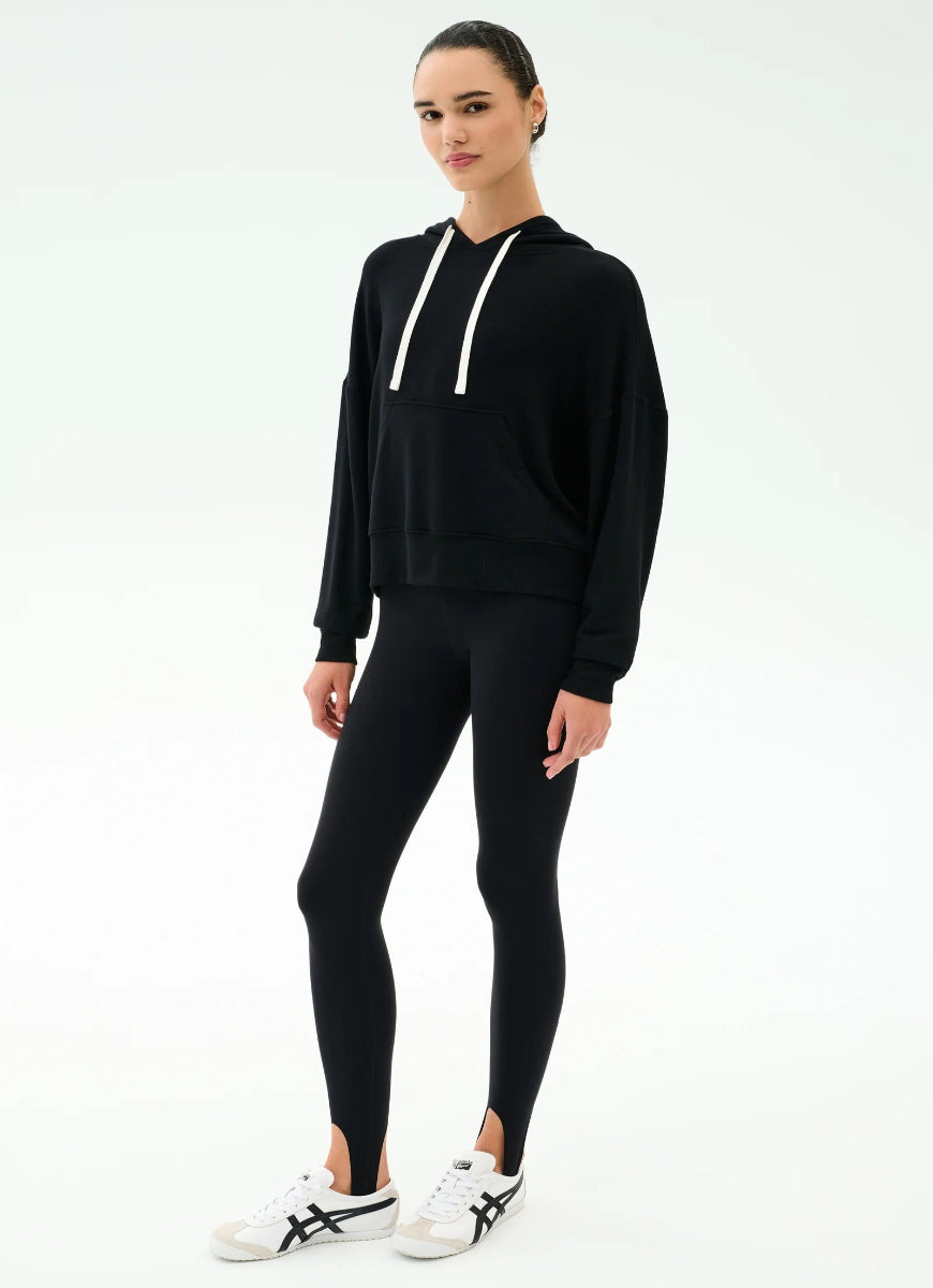 Person wearing a black hoodie and leggings set on a white background