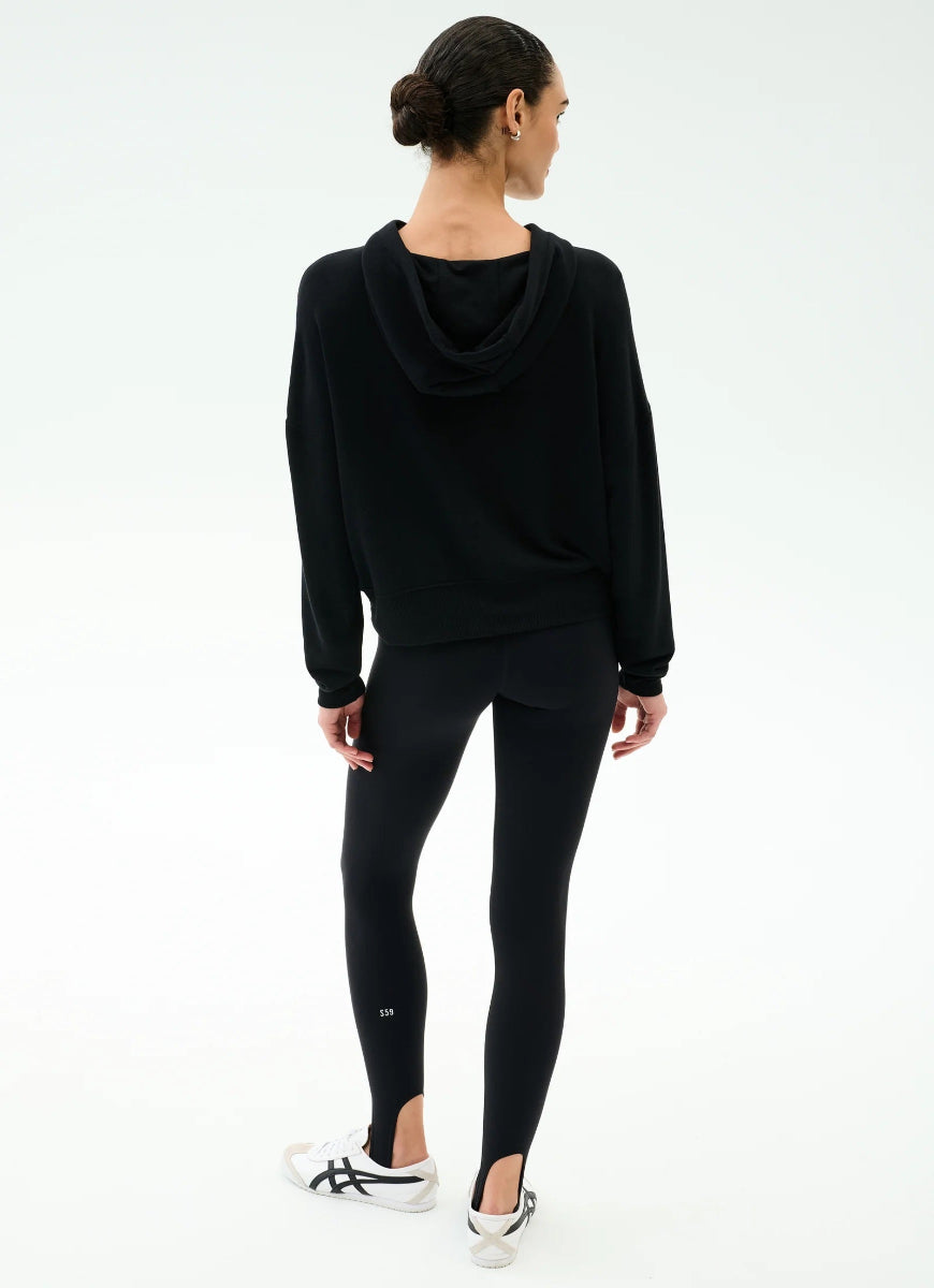 Person wearing a black hoodie and leggings on a white background