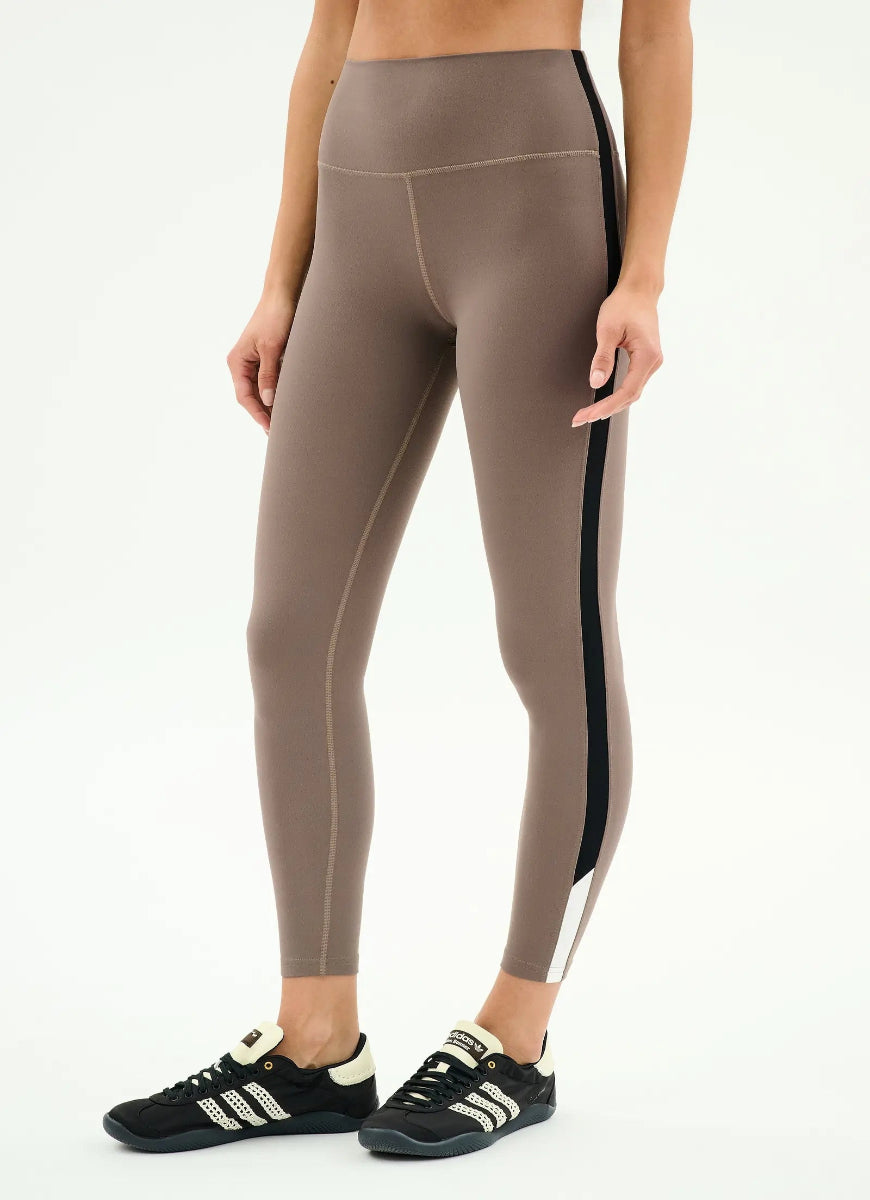 Person wearing brown leggings with black stripes on a white background