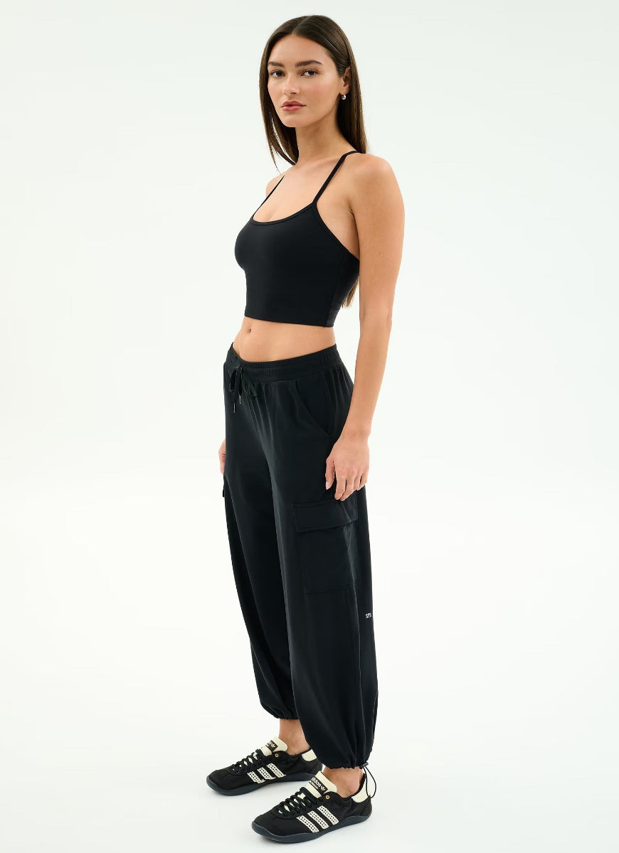 Woman wearing a black athletic outfit with Adidas shoes on a white background