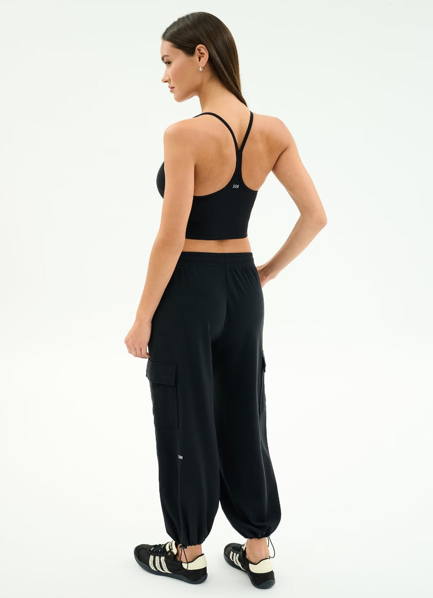 Woman wearing a black sports bra and cargo jogger pants on a white background