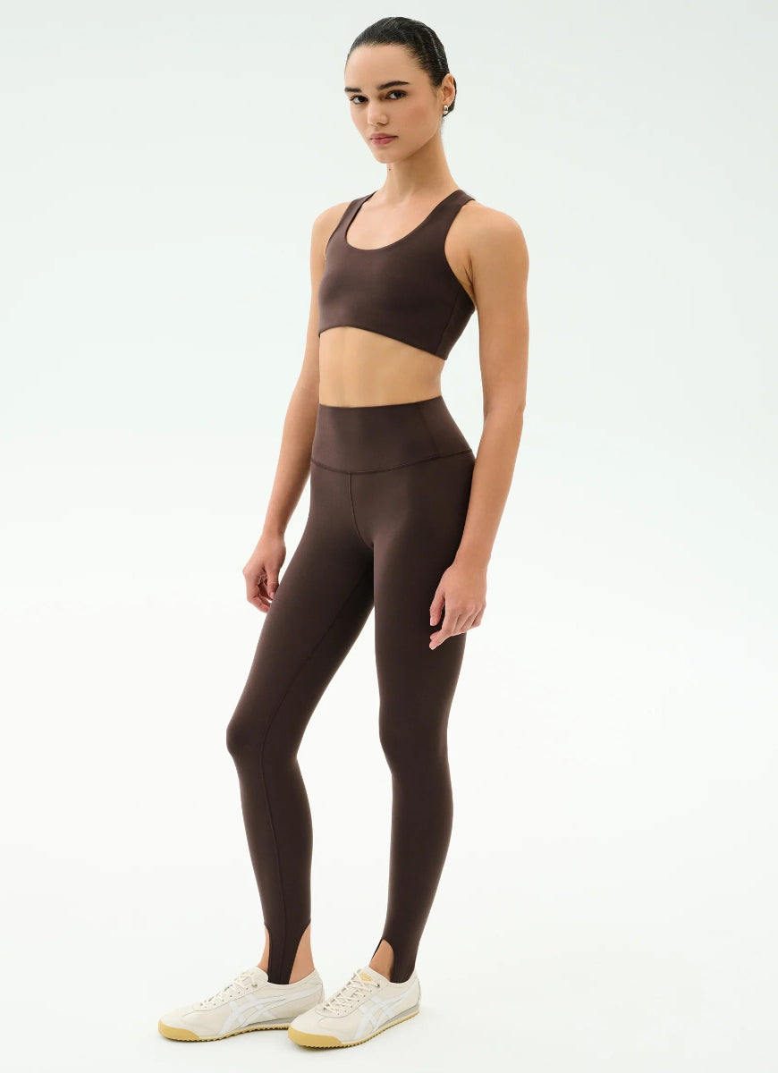 Woman wearing a brown sports bra and leggings set on a white background