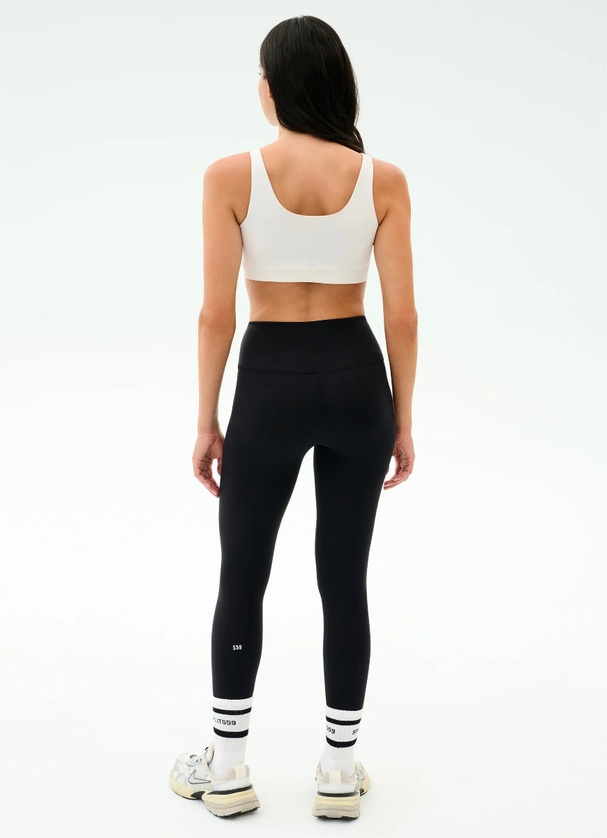 Person wearing a white sports bra and black leggings on a white background