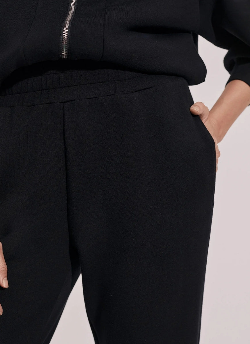 Varley The Slim Zip Hem Pant 29.5” in Black Close Up Front View With Hand in Pocket