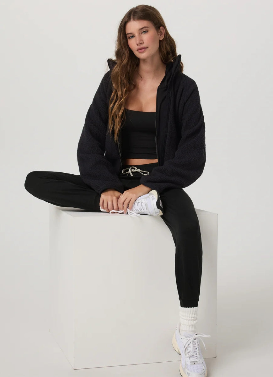 Vuori Women's Performance Jogger Long in Black Heather Front View With Model Sitting Down