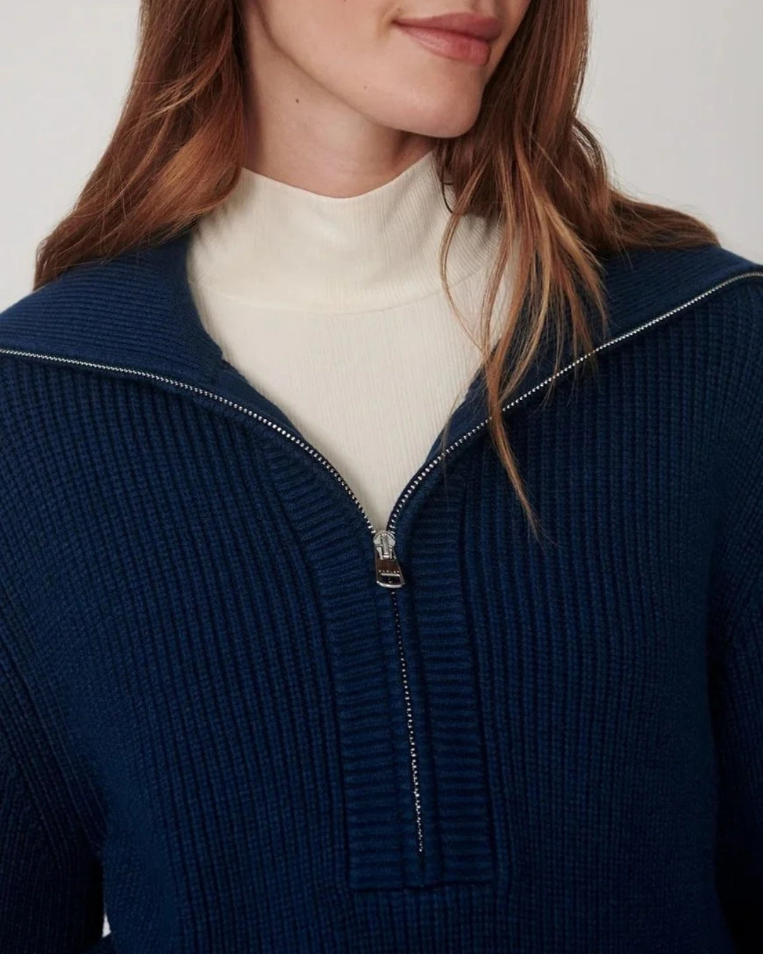Women's navy blue ribbed half-zip knit sweater layered over a cream top from Varley at relevé