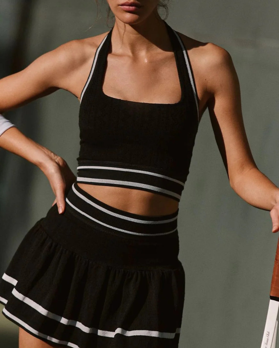 Woman wearing a black and white sports outfit against a neutral background
