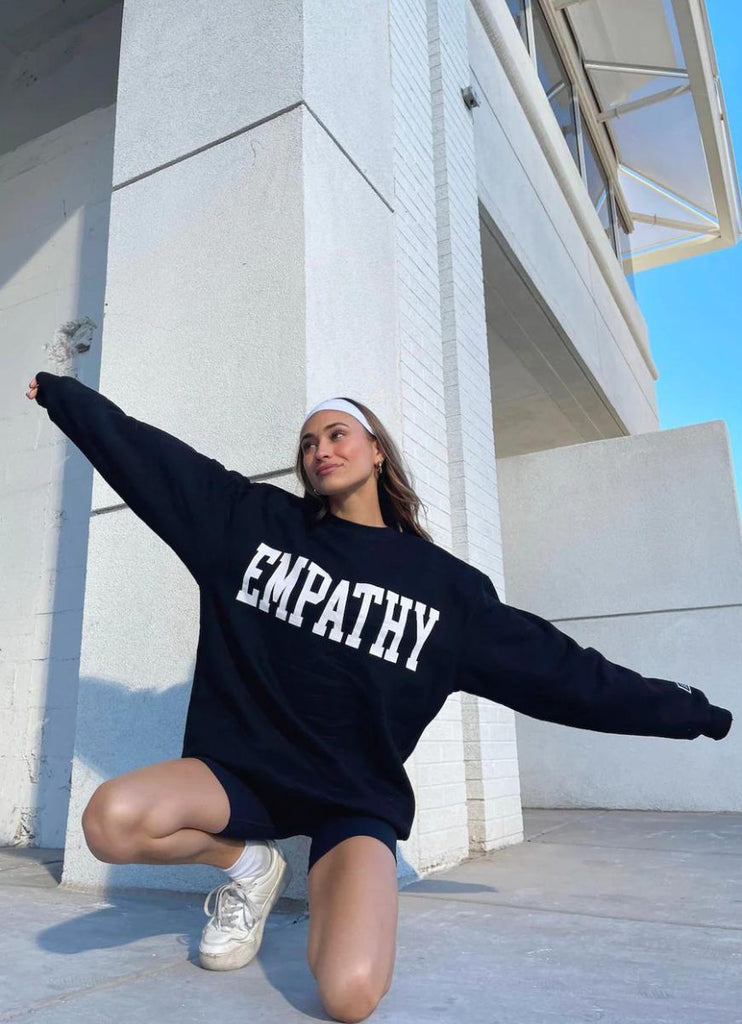 The Mayfair Group Empathy Always Women's Crewneck in Black Front View with Model Crouched Down
