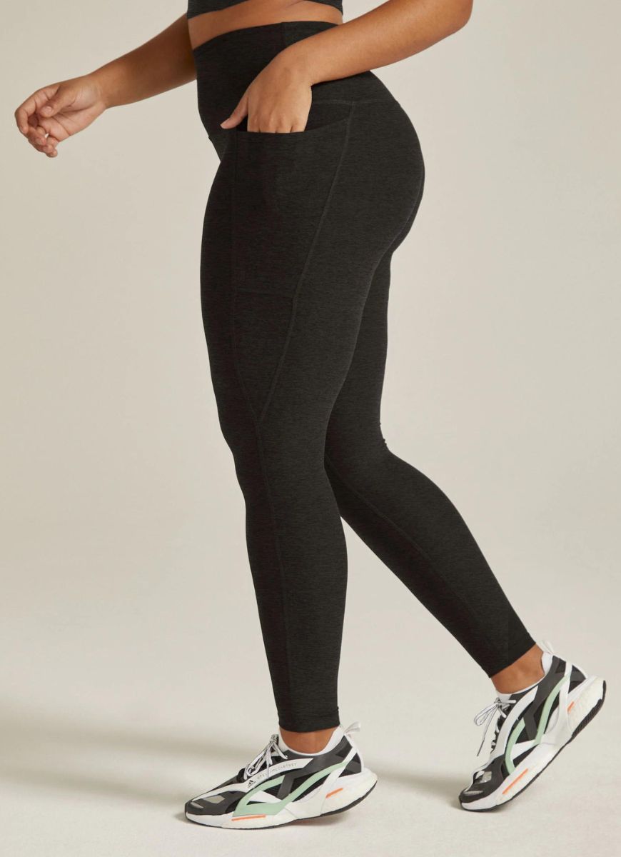 Beyond Yoga Out of Pocket High Waisted Midi Legging in Darkest Night Waist Down Side View With Hand in Pocket