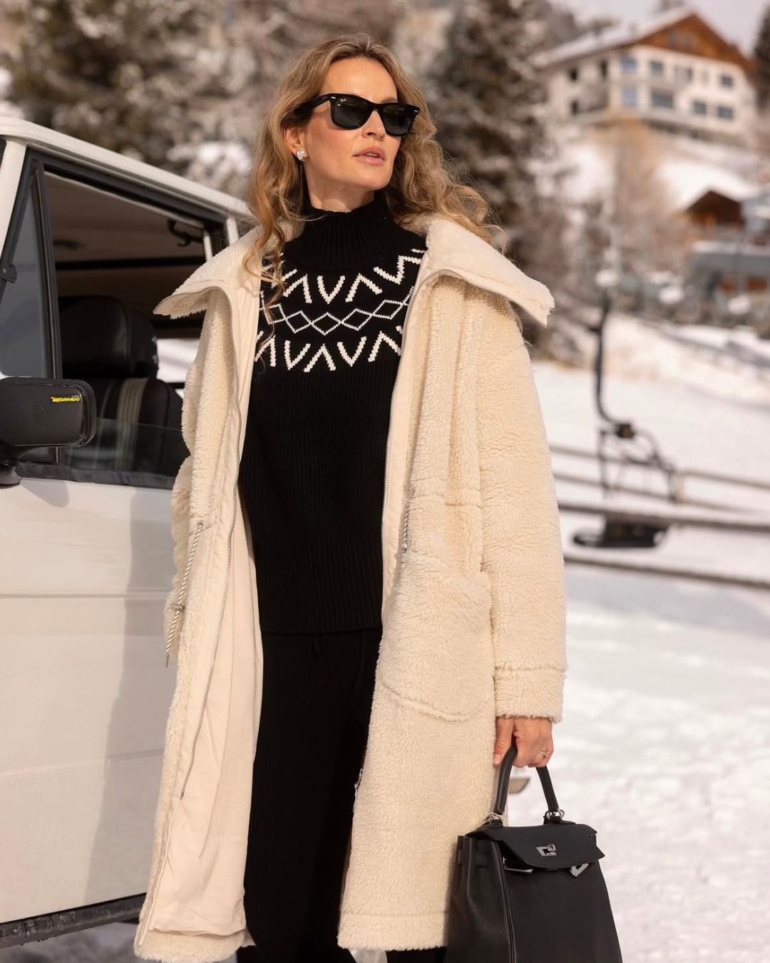 Model Standing at a Ski Resort Wearing the Varley Logan Sherpa Coat in Sandshell