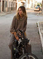 The Upside Castilla Millie Knit Sweater in Pebble Shown on Model Sitting on Motorcycle. 