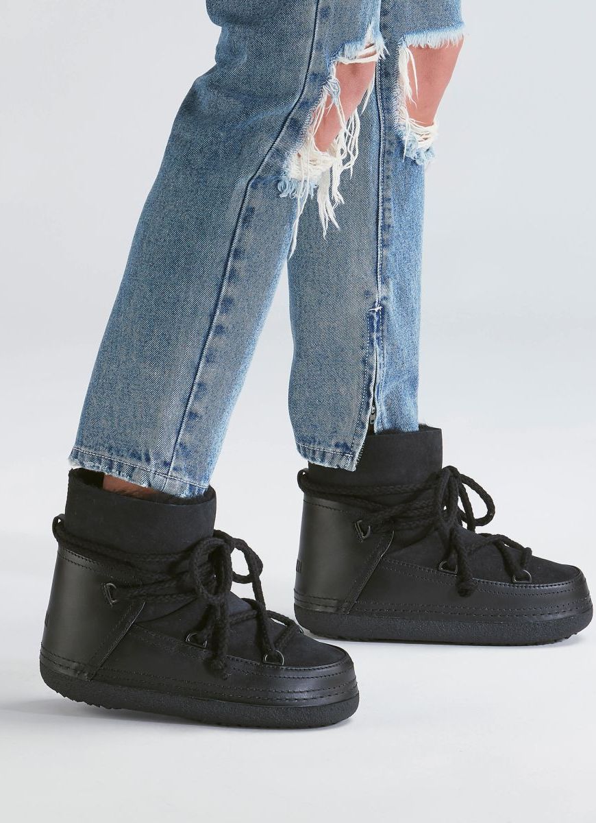 INUIKII Classic Women's Winter Boot in Black Shown on Model Wearing Jeans Side View