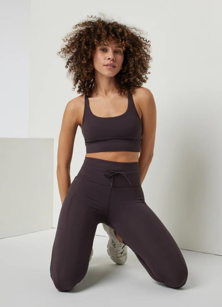 Vuori Daily Pocket Legging in Sangria Model Kneeling in a Pose