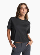 vuori Women's Energy Tee in Black Thigh Up Front View with Hands in Pockets