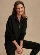 Varley Hawley Half Zip Sweat in Black Model Sitting on a Stool