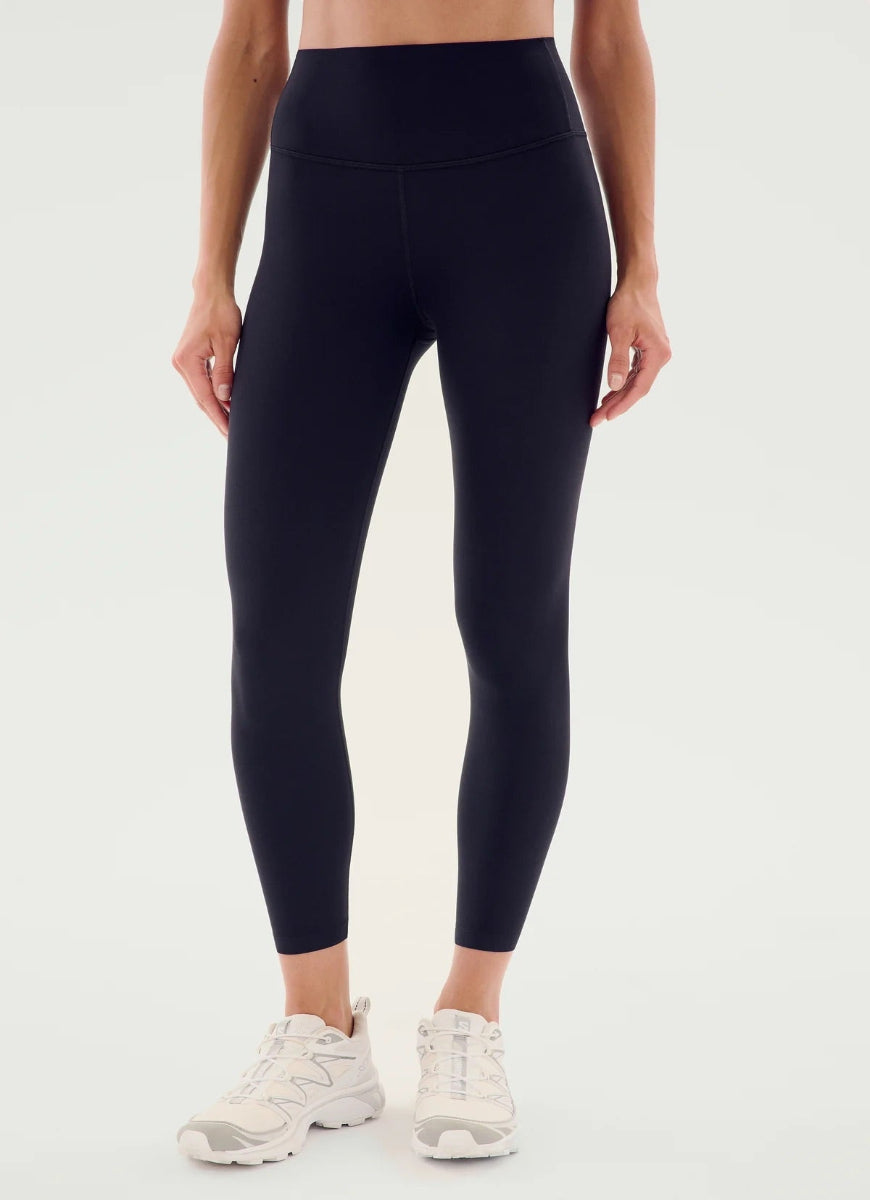 Person wearing black leggings and white sneakers on a white background