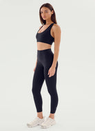 Woman wearing black athletic top and leggings on a white background