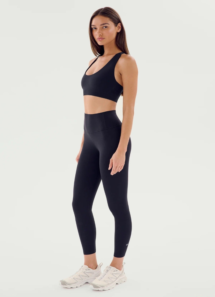 Woman wearing black athletic top and leggings on a white background