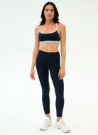 Woman wearing a black sports bra and leggings set on a white background