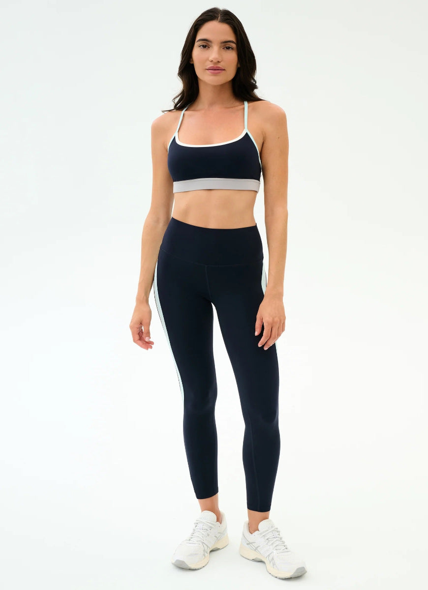 Woman wearing a black sports bra and leggings set on a white background