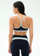 Woman wearing a black and green sports bra and leggings on a white background