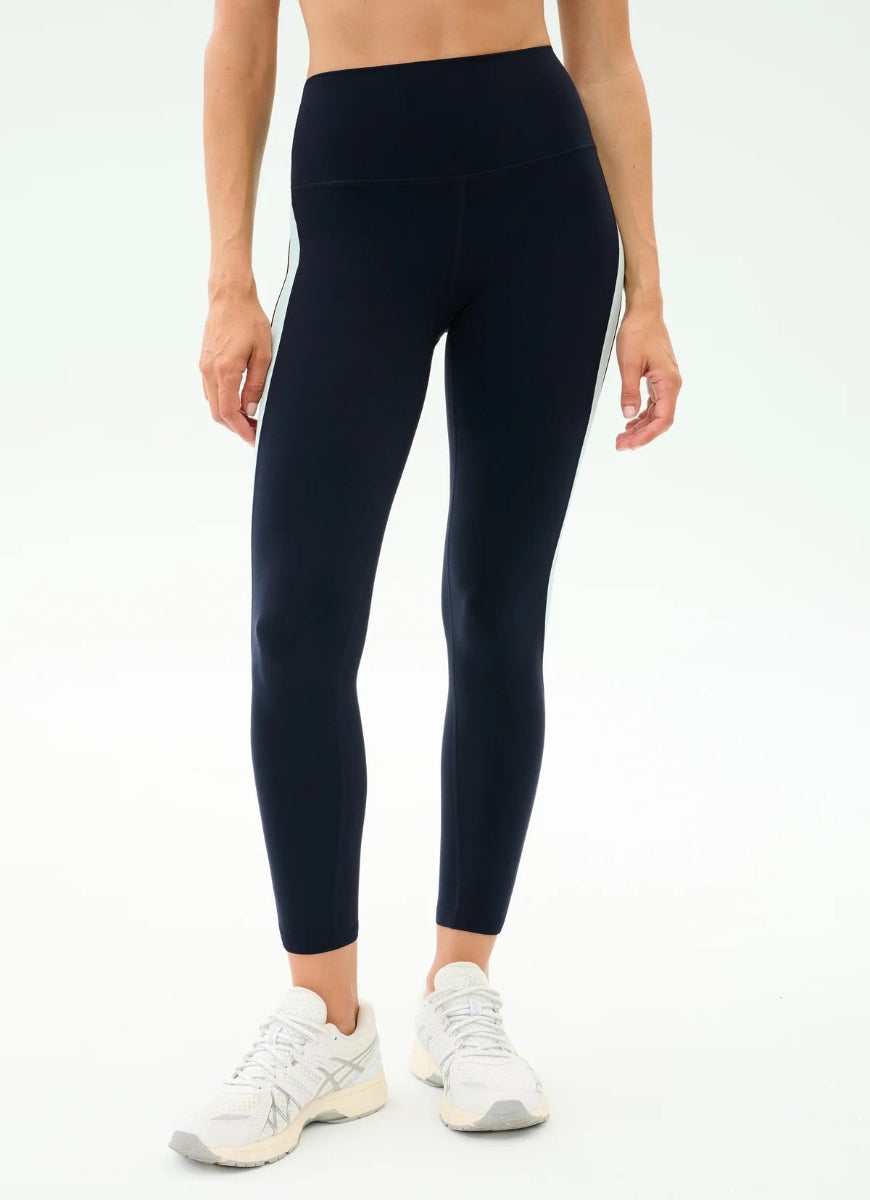 Person wearing black leggings and white sneakers on a white background