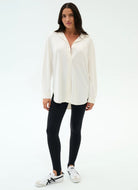 Woman wearing a white blouse and black leggings on a white background