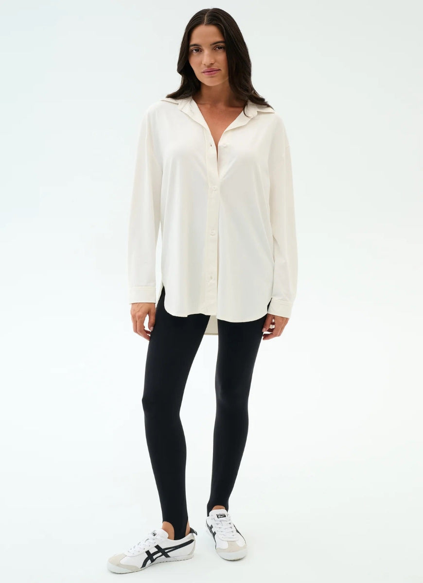 Woman wearing a white blouse and black leggings on a white background