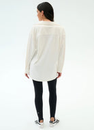 Woman wearing a white shirt and black leggings on a white background