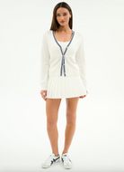 Woman wearing a white cardigan with blue trim on a white background
