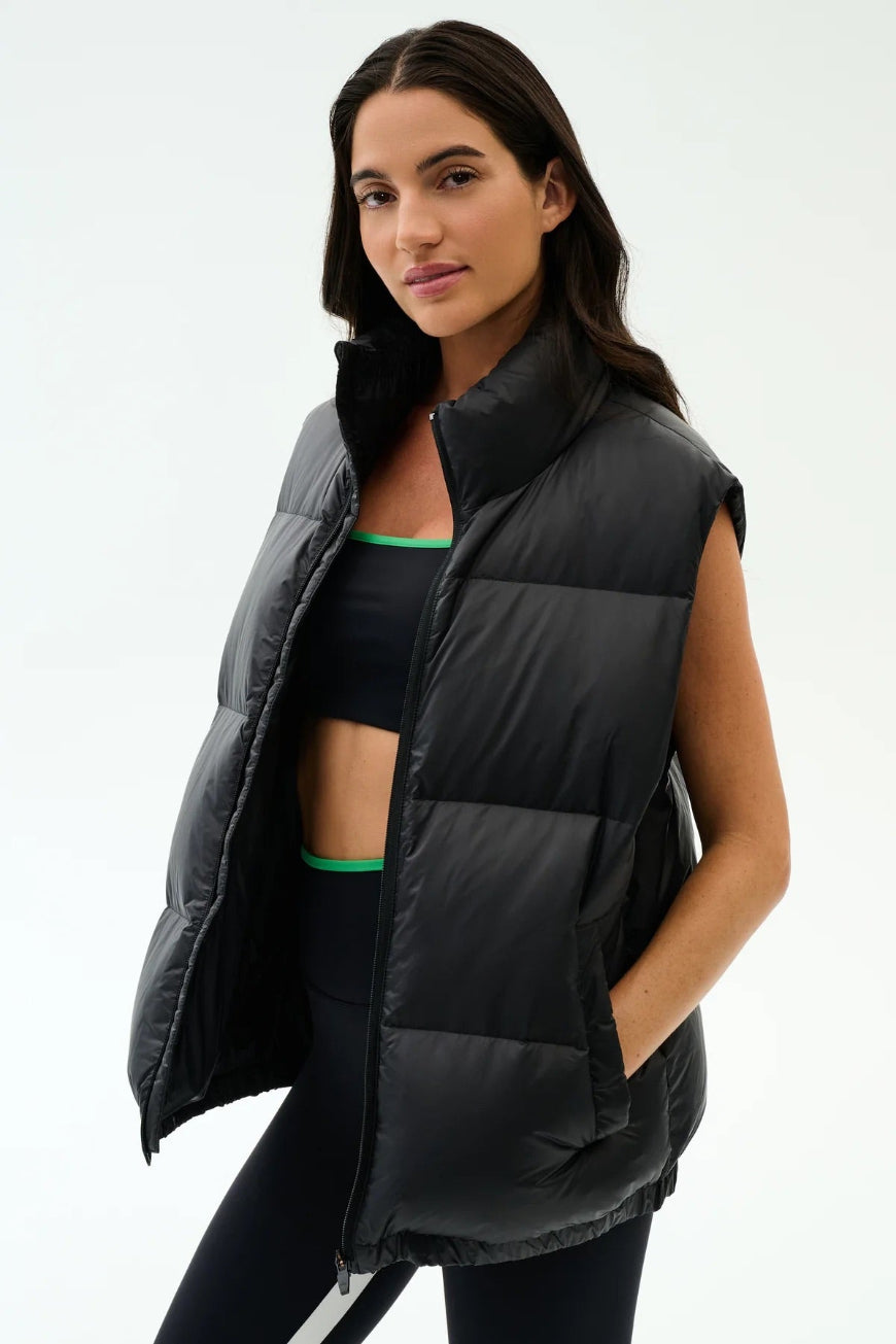 Woman wearing a black puffer vest on a light gray background