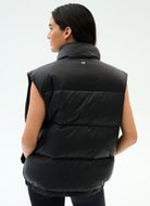 Person wearing a black puffer vest on a white background