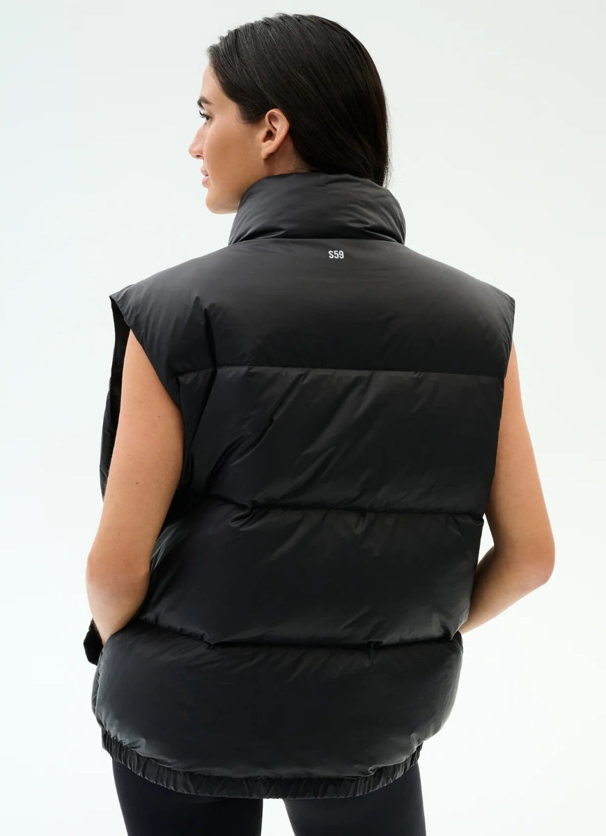 Person wearing a black puffer vest on a white background
