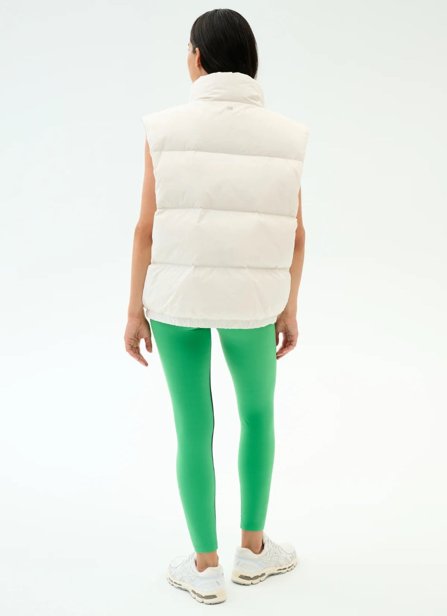 Person wearing a white puffer vest and green leggings on a white background